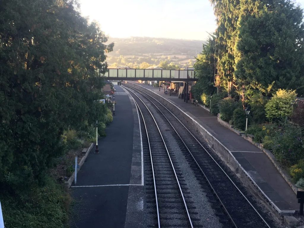 Train station rail tracks with green trees.