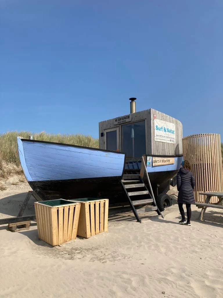 Sauna shaped like a ship on a sandy beach.