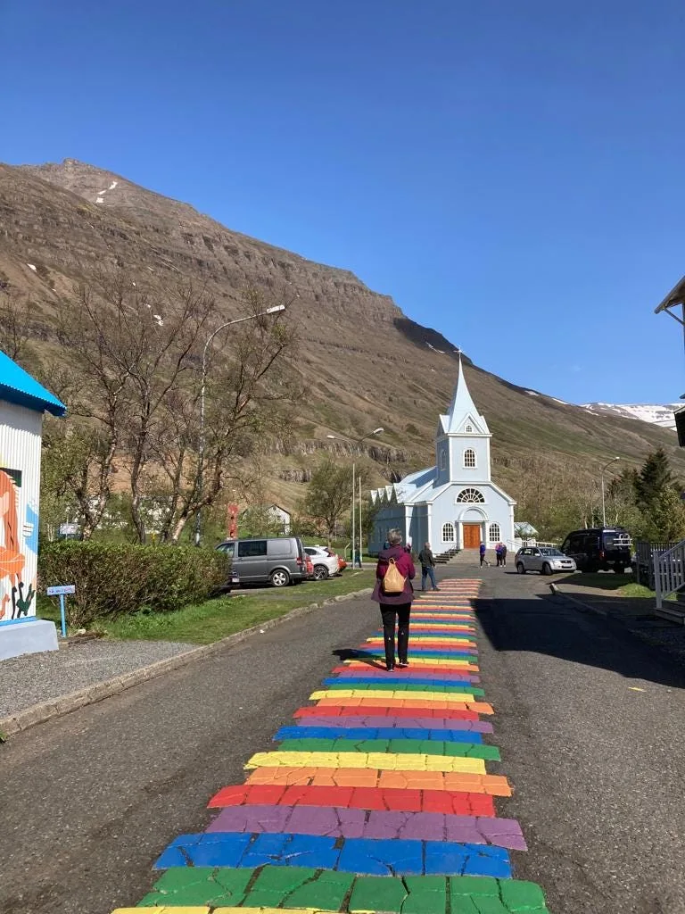 Rainbow walk leading to a blue church