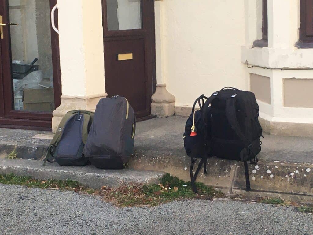 Waiting for a bus in Wales with a total of four backpacks. We're each practicing one backpack travel.