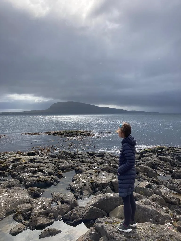 Rose standing on rocks looking out to sea.