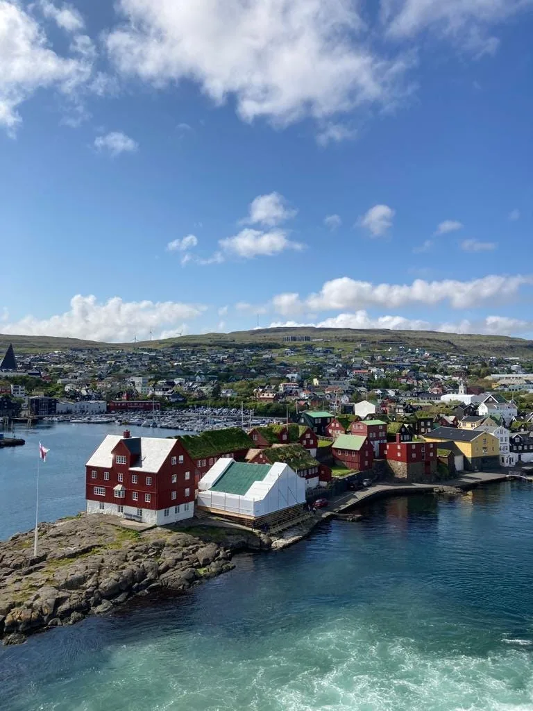 View of Tórshavn Harbor with red white and green wooden houses on a jetty.