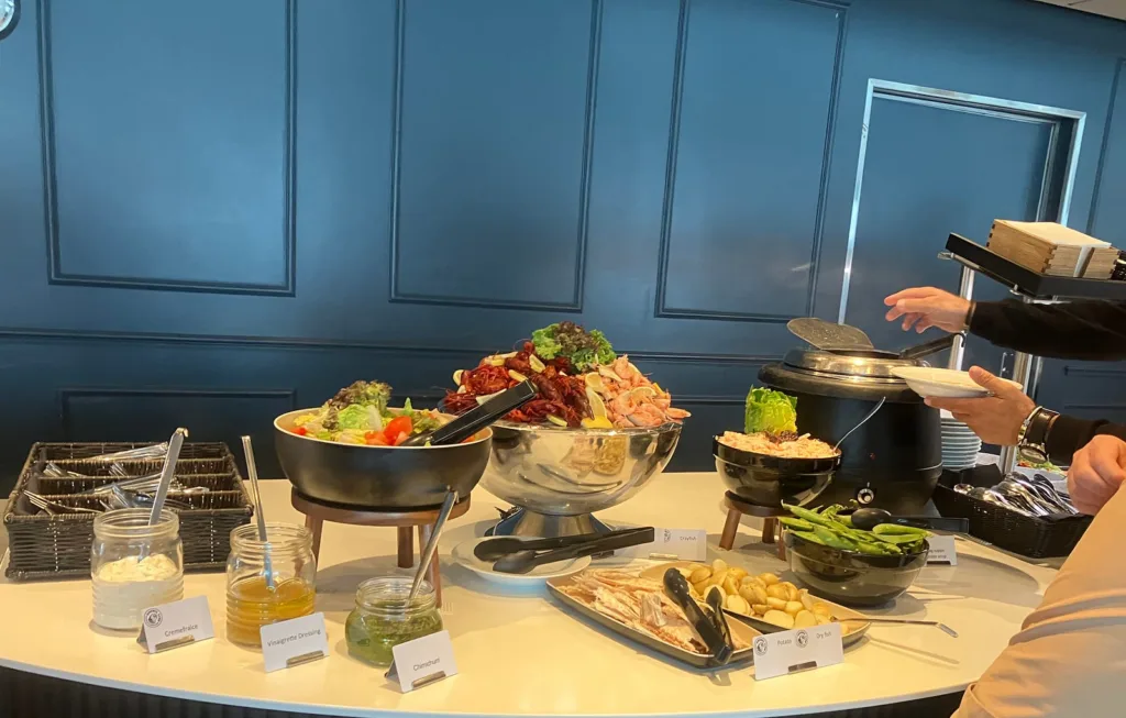 Buffet table with soup, shrimp, salad, and other dishes.