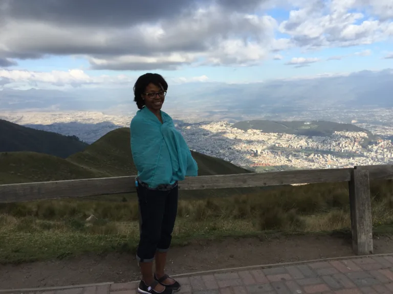 Aneisha wearing black pants and blue shawl in front of mountain in Ecuador