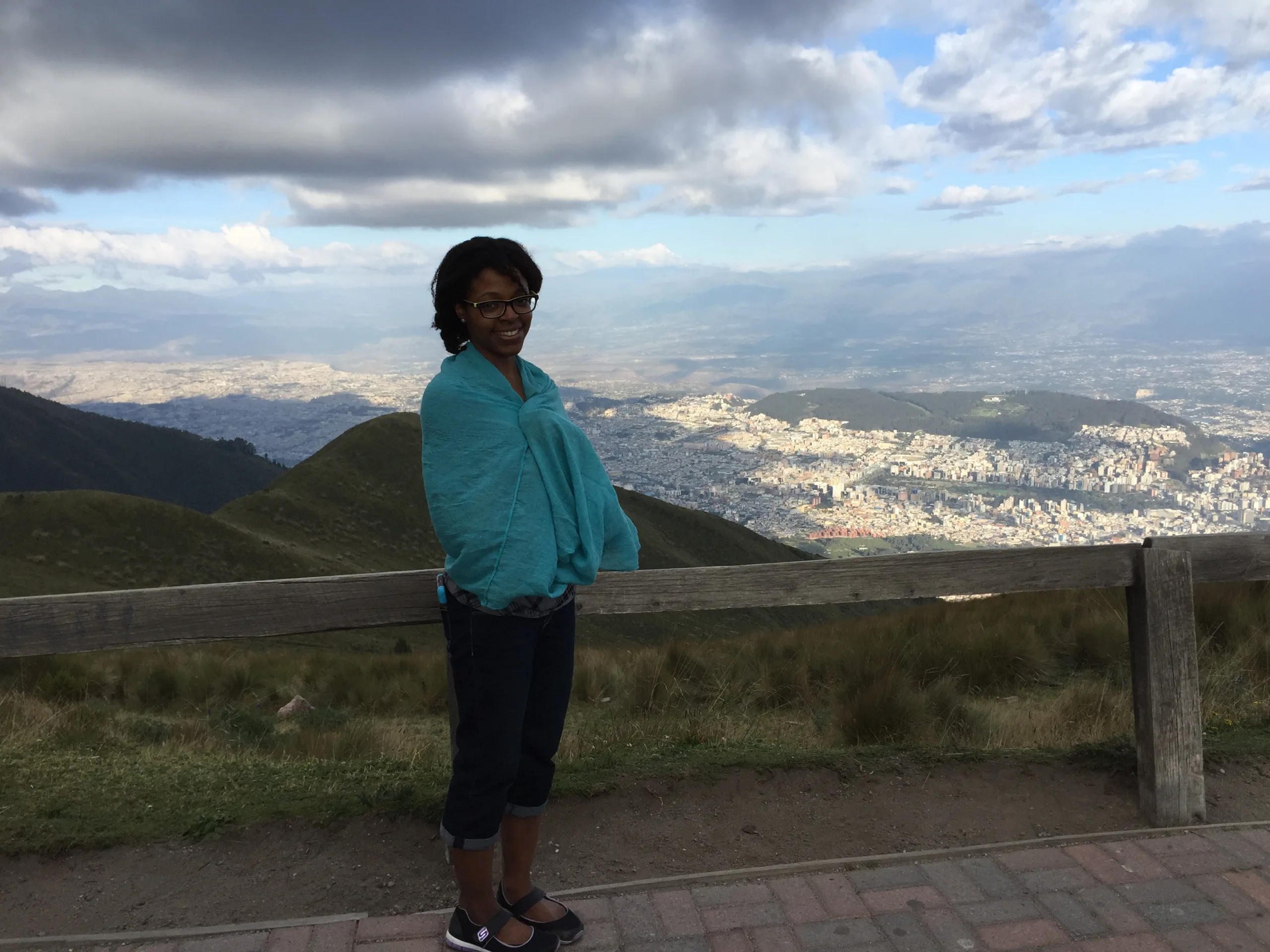 Aneisha wearing black pants and blue shawl in front of mountain in Ecuador