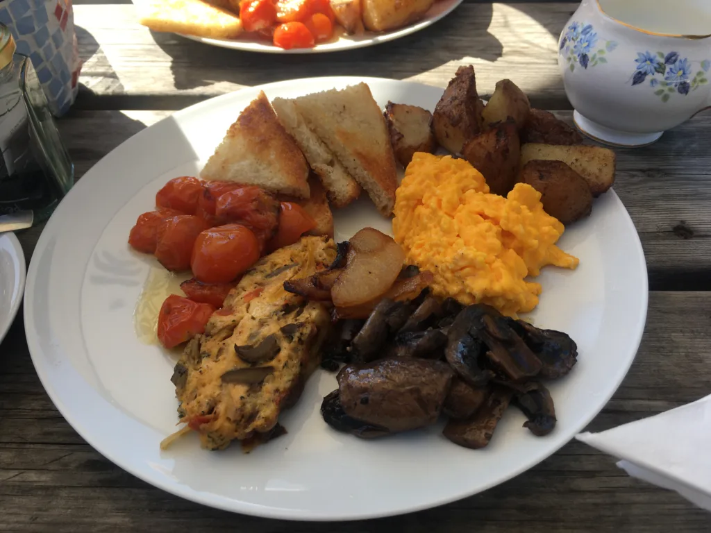 English vegetarian breakfast for sensory seeking autism. Scrambled eggs, toast, potatoes, tomatoes, omelette, apples, and mushrooms.