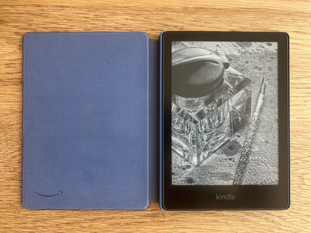 Open kindle in a blue case on a wood floor.