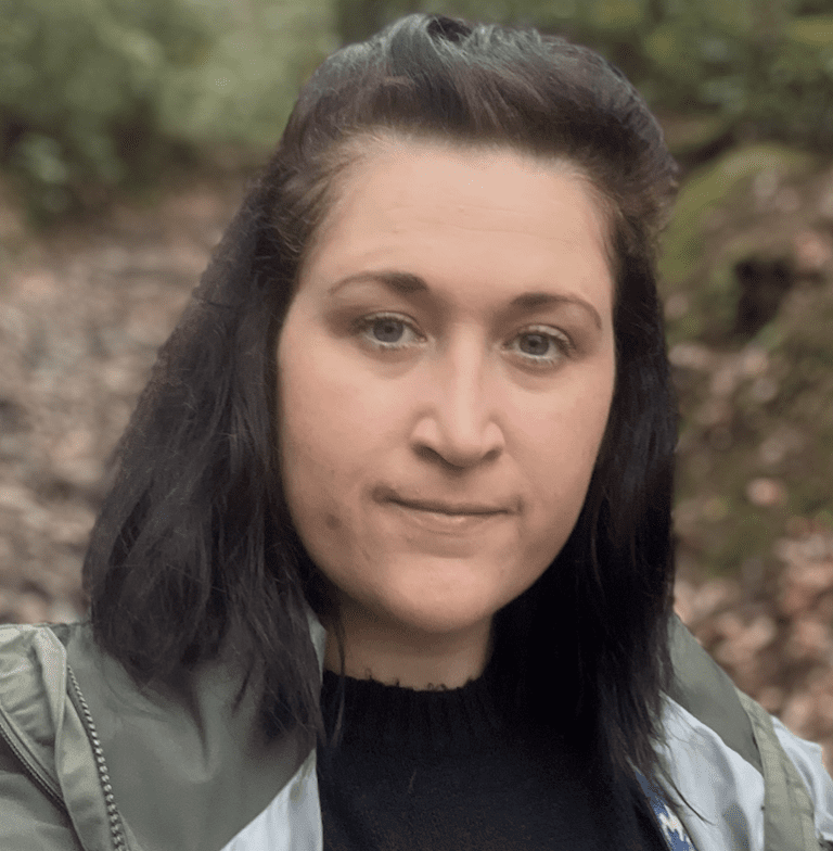 Headshot of Lisa Guard with dark medium length hair in the woods.