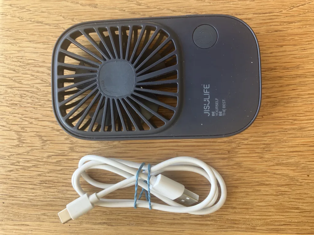 Small black fan and white cord on a wood floor.