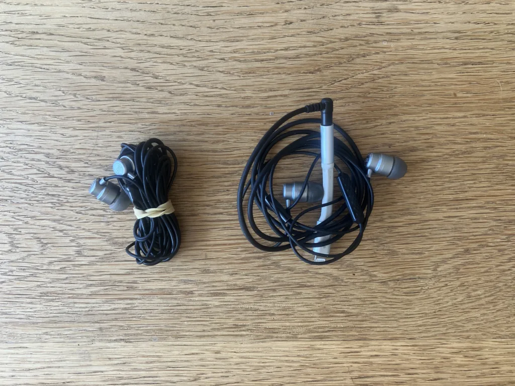 Two black earphone cords rolled up on wood floor.