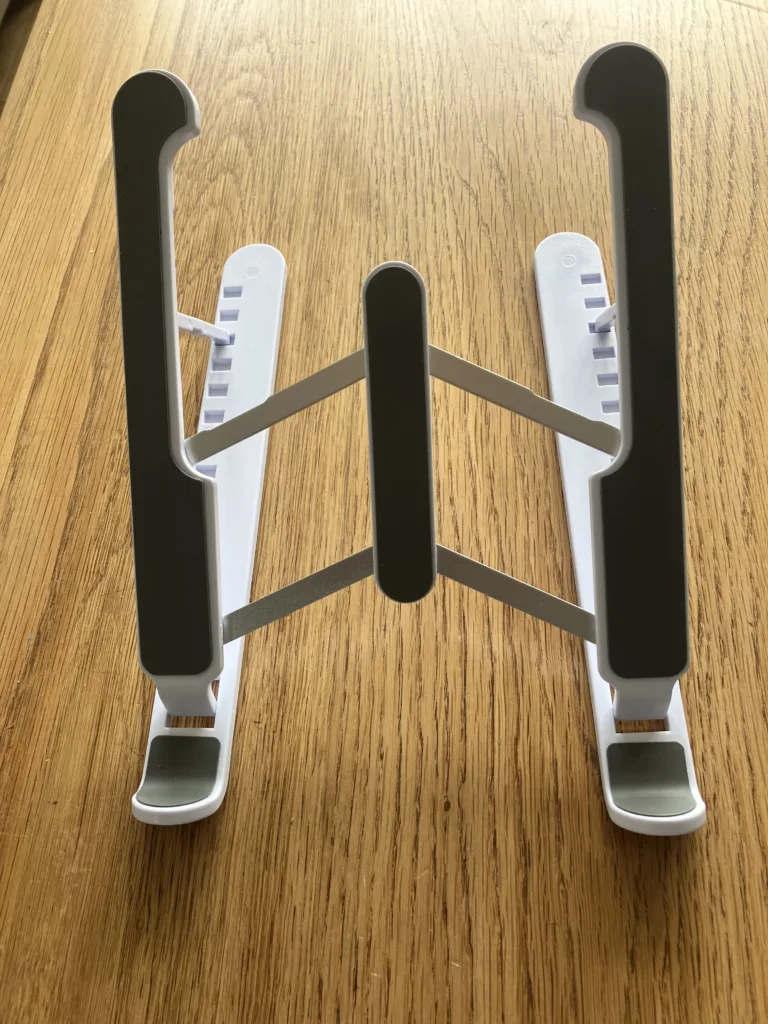 Foldable plastic laptop stand on a wood floor.