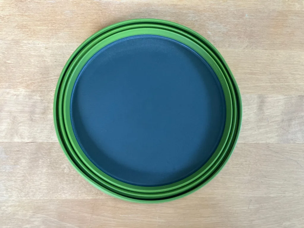 Green and grey flat bowl on wooden table.