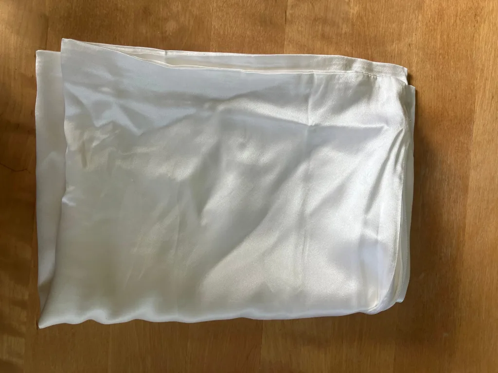 folded white silk pillowcase on wooden table.